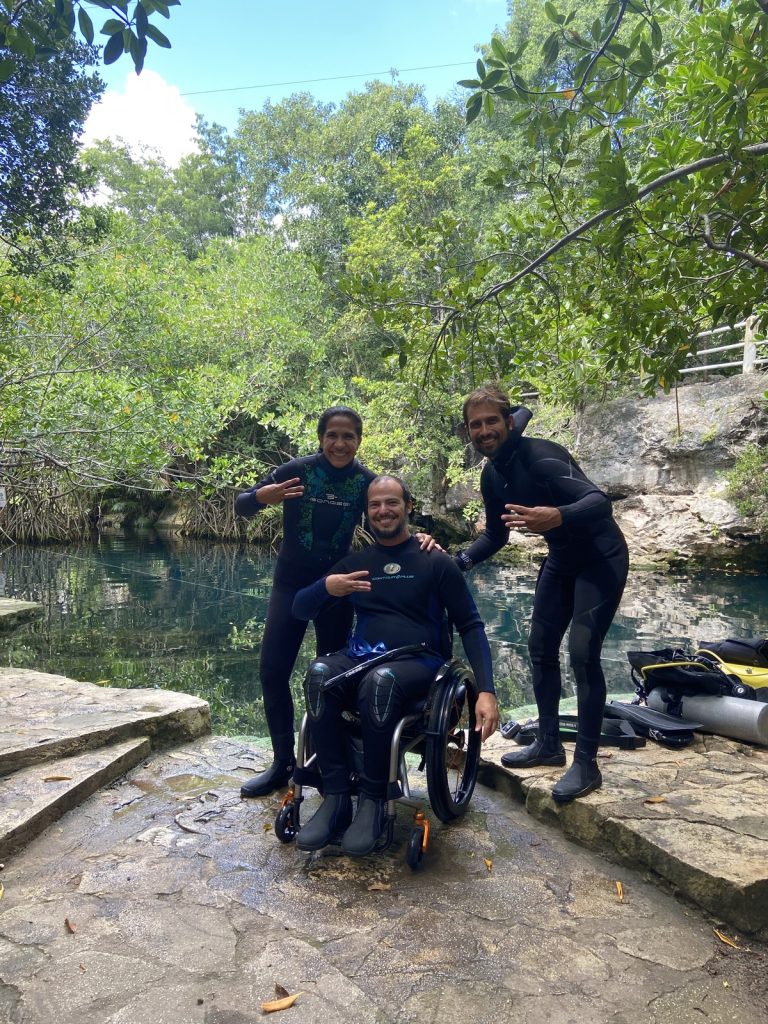 Three members of The Dive Machine team in wetsuits at a cenote in the Riviera Maya